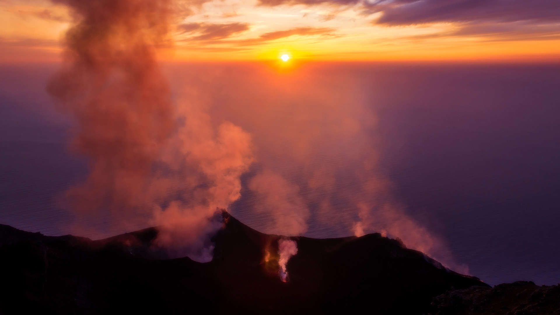 Crateri fumanti dello Stromboli al tramonto sul mare